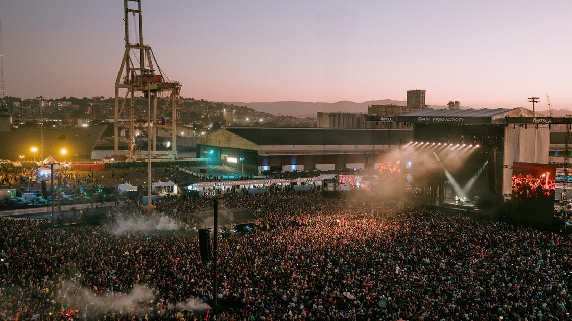 Publikum am Pier 80 in San Francisco im Sonnenuntergang, Hafenkräne über der Bühne
