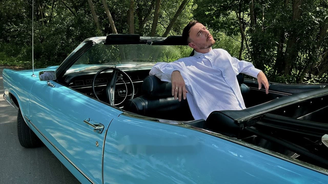 Ivan NAVI in a light blue convertible among trees